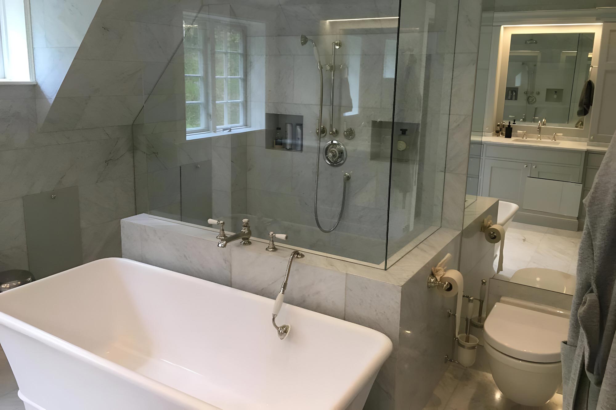 Ett grått badrum med badkar och toalett