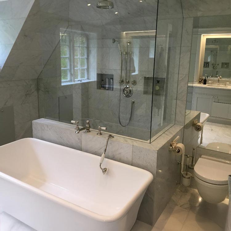 Ett grått kaklat badrum med badkar och en toalett